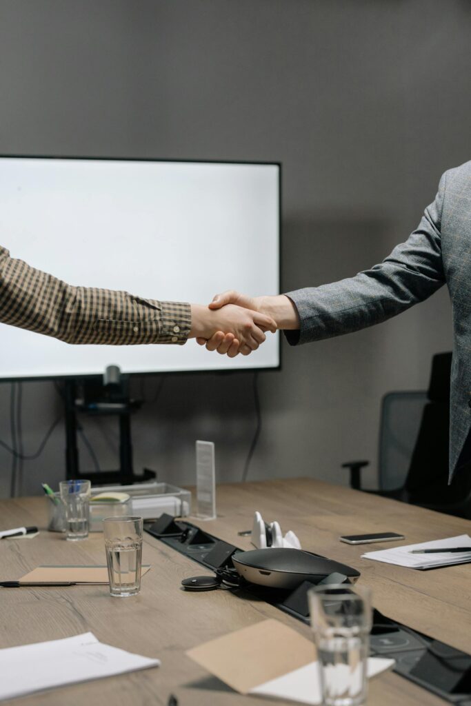 Business partners shaking hands over documents to formalize a founder agreement