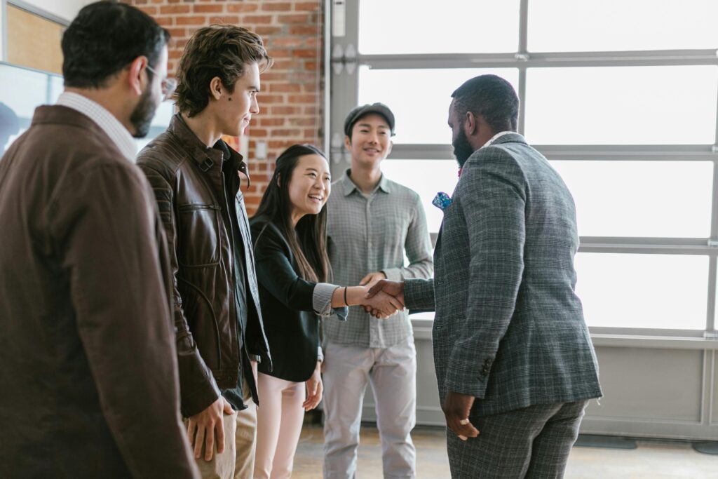 Two business professionals shaking hands as new co-founders with team members looking on