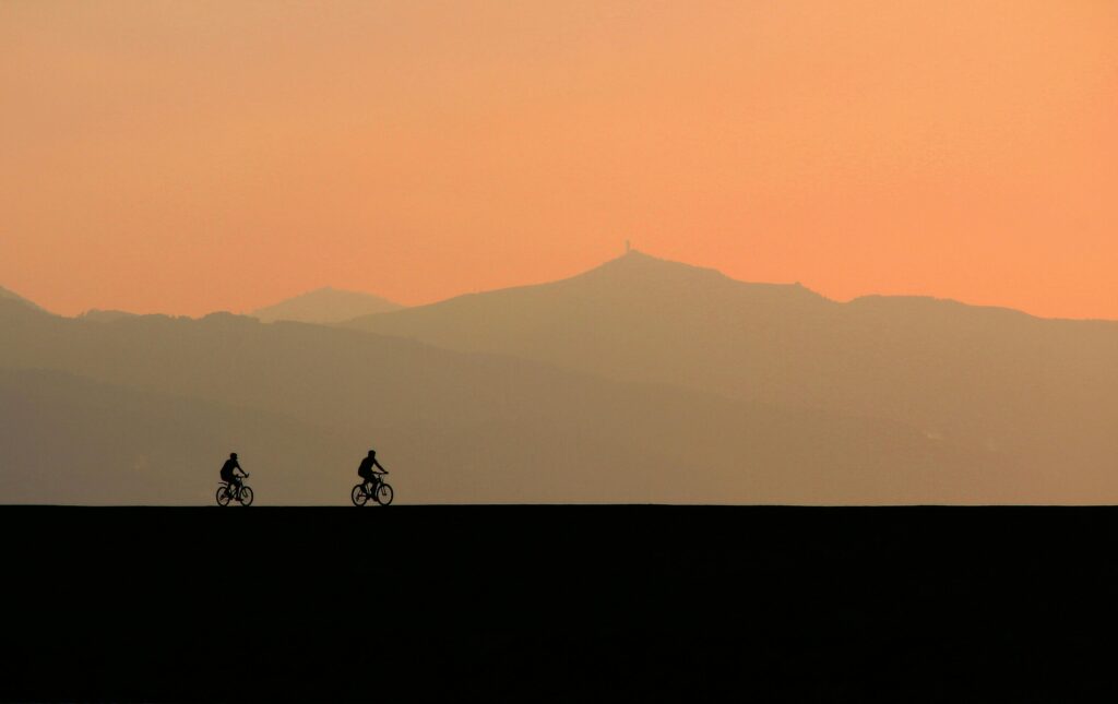 Two co-founders cycling side by side toward the horizon at sunset — a metaphor for shared vision and direction in a startup partnership
