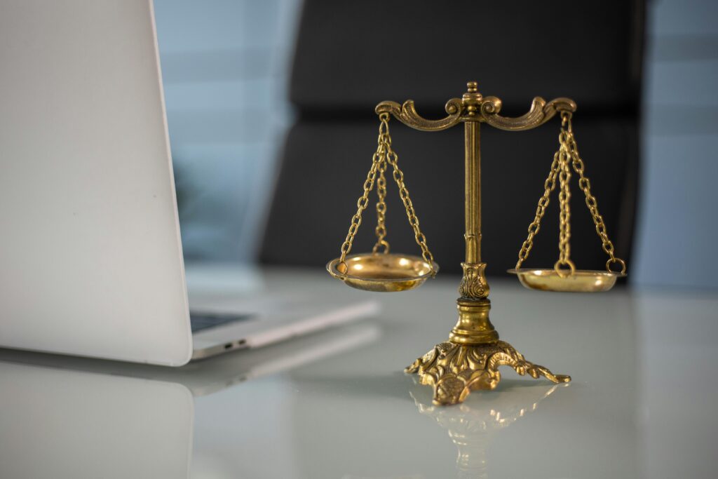 Golden scales of justice beside a laptop, symbolising the legal essentials every startup founder needs — shareholders agreement, directors service agreement and employment contracts