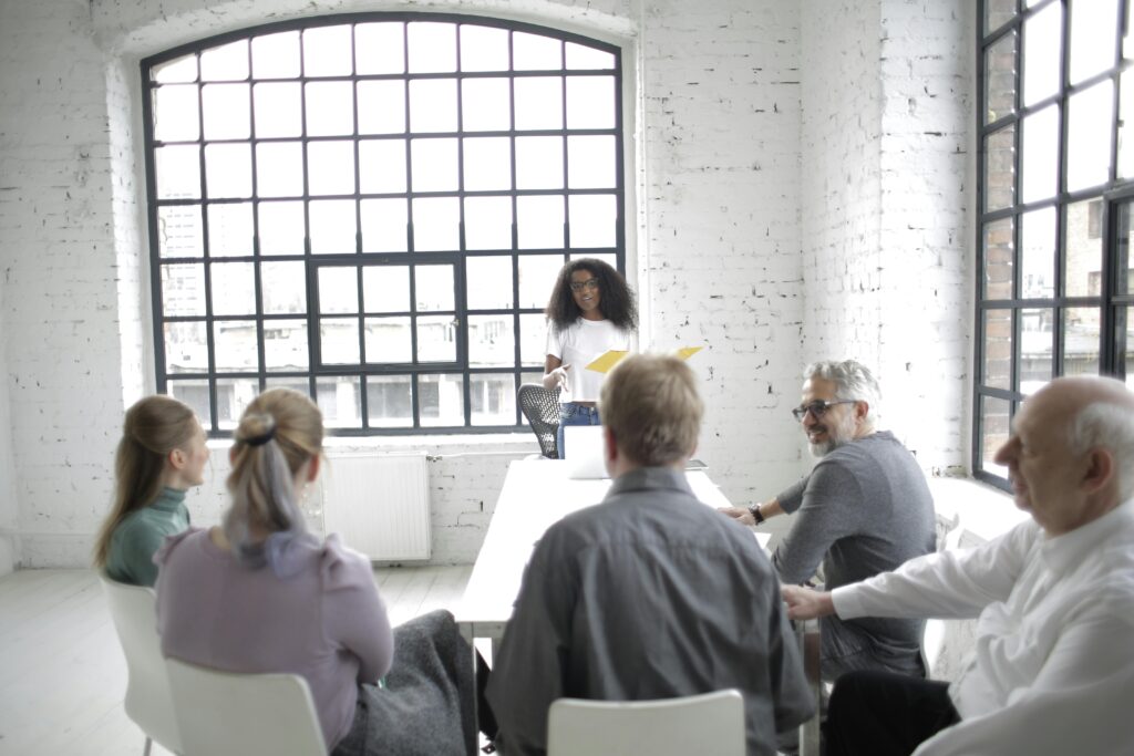 A woman leads a team meeting in a bright industrial office, representing servant leadership in action