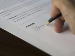 Close-up of a hand signing a formal contract or legal agreement – illustrating the importance of written agreements in co-founder relationships