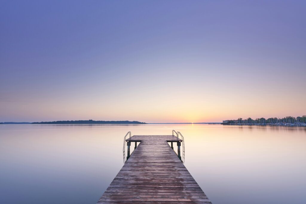 Calm lake with wooden pier at sunset representing stable, forward-looking leadership
